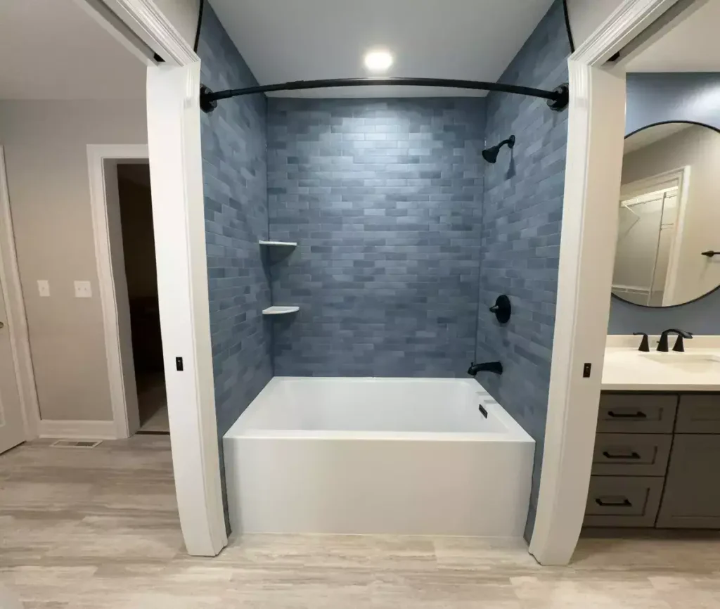 Deep bathtub and sleek blue tile surround with black fixtures by Stately Kitchen and Bath in Orchard Park, NY.