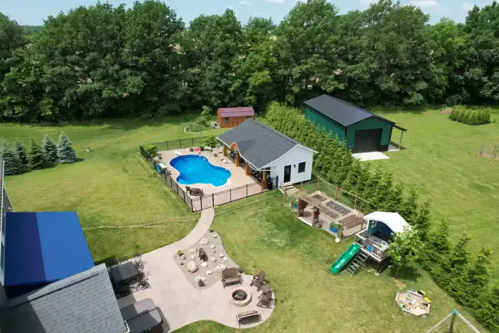 Aerial view of the pool house addition in Akron, NY, featuring the pool, landscaping, and surrounding property, a project by Stately General Contracting.