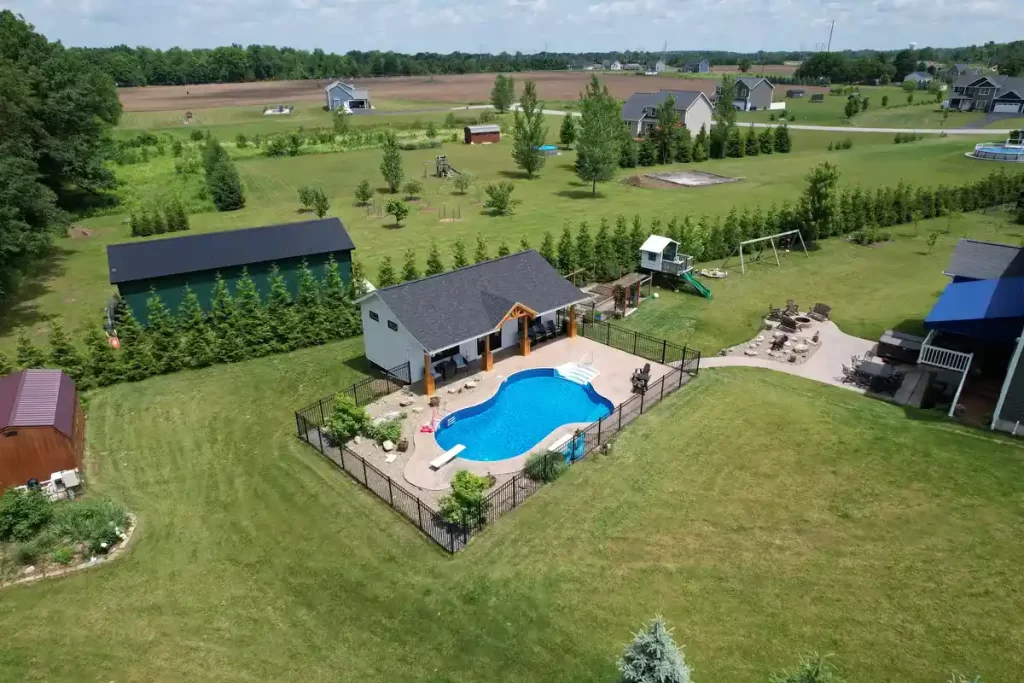 Wide aerial shot of the pool house addition in Akron, NY, highlighting the pool and extensive backyard, designed by Stately General Contracting.