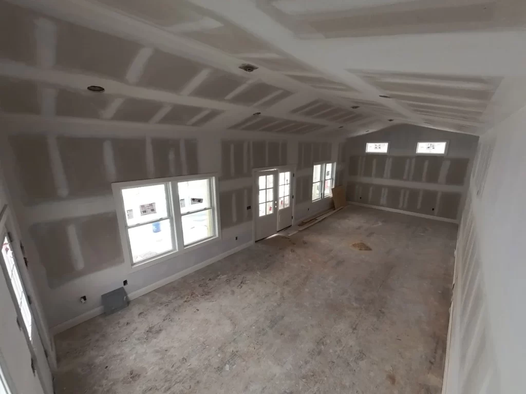 Spacious pool house interior under construction with freshly installed drywall.