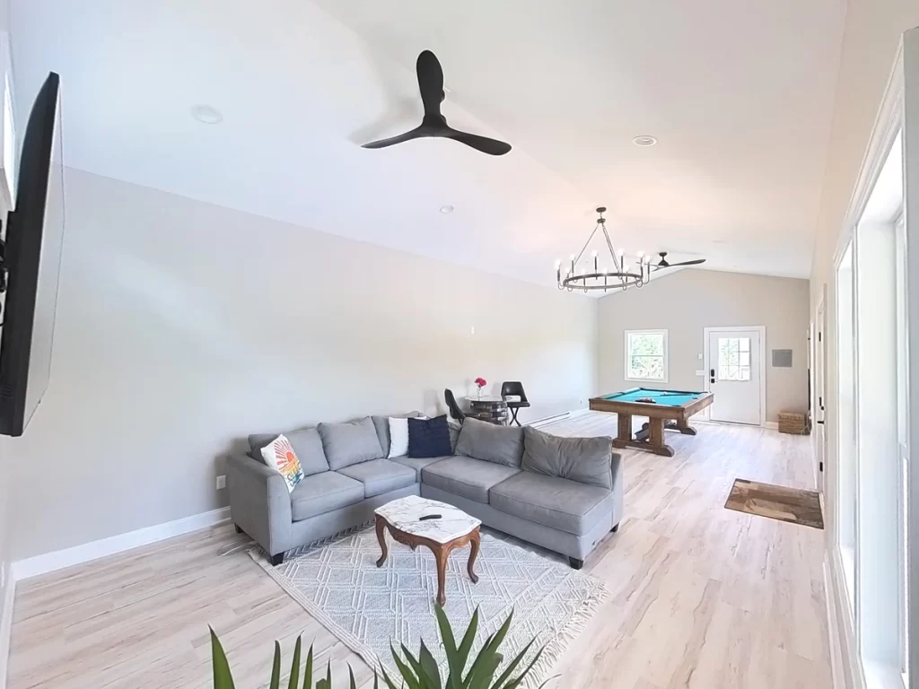 Interior of the pool house addition in Akron, NY, with a focus on the sectional sofa, coffee table, and open space designed by Stately General Contracting.