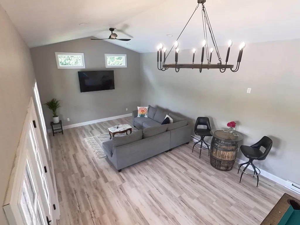 Interior shot of the pool house addition in Akron, NY, featuring a sectional sofa, TV, and chandelier, highlighting the open and airy layout by Stately General Contracting.