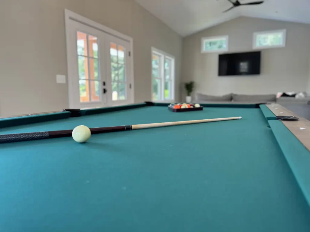 Close-up of the pool table inside the pool house addition in Akron, NY, with doors leading to the pool area in the background, a project by Stately General Contracting.