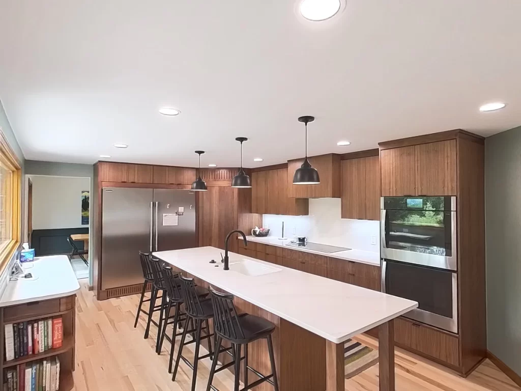 Completed kitchen remodel by Stately Kitchen and Bath featuring island with seating, custom cabinets, and stainless steel appliances.