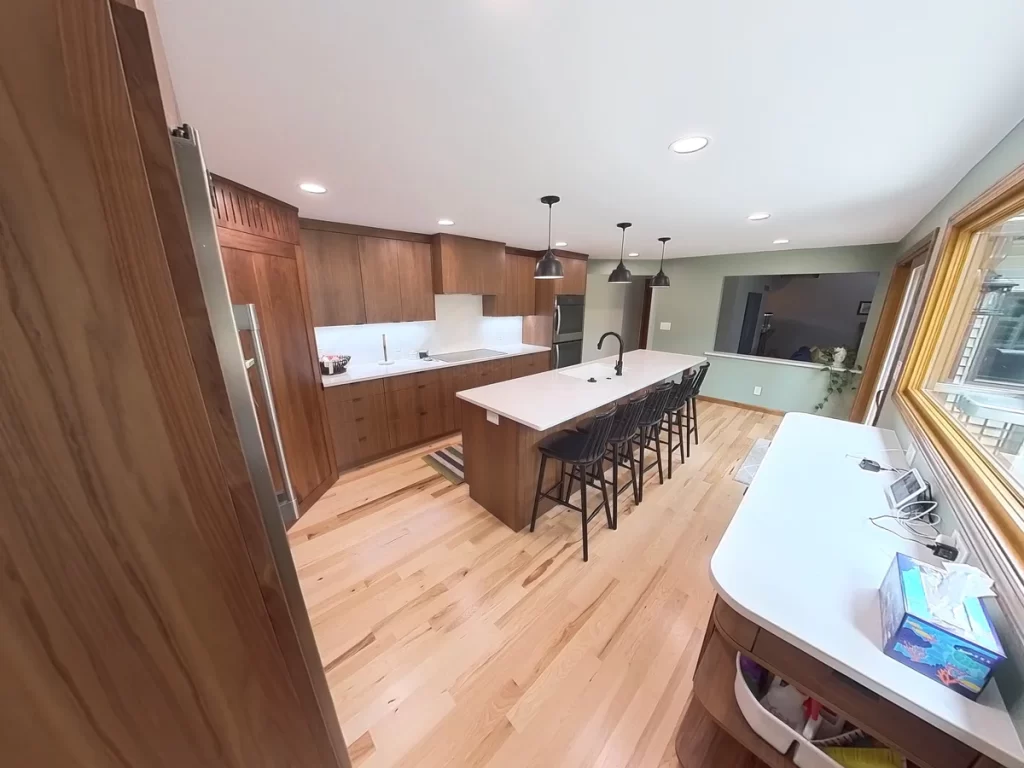 Modern kitchen remodel by Stately Kitchen and Bath showcasing large island, custom cabinetry, and hardwood floors.