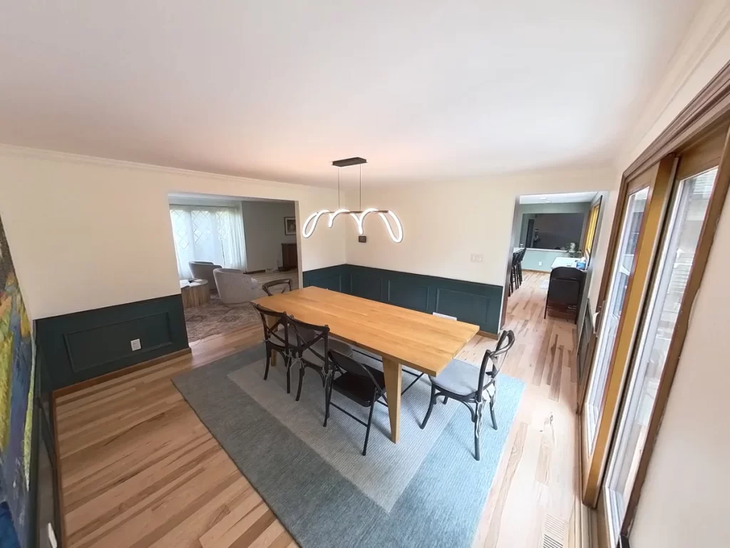 Modern dining area with wooden table and contemporary chandelier in Buffalo, NY after Stately Kitchen Remodel.