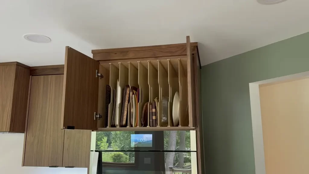 Upper kitchen cabinet with organized storage for trays and cutting boards in Buffalo, NY after Stately Kitchen Remodel.