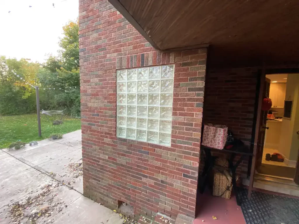 Brick exterior wall of a home in Buffalo, NY with a glass block window before remodeling.