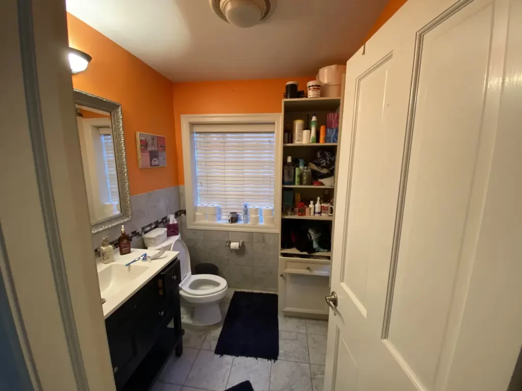 Orange bathroom with a window and white tiles in Buffalo, NY before renovation.