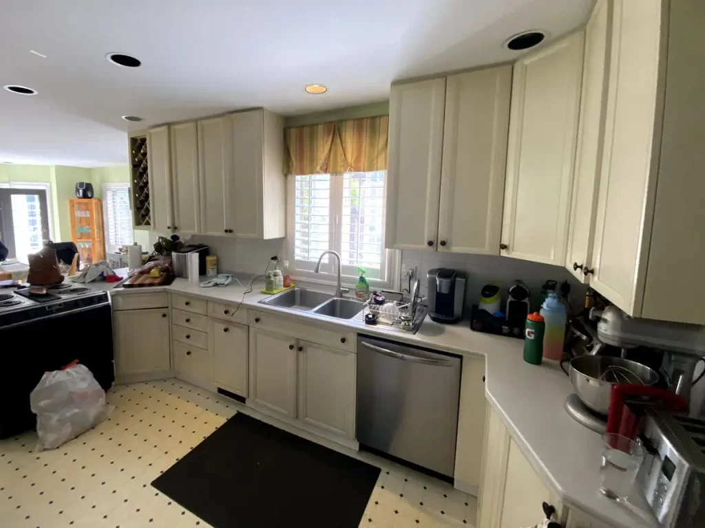 Kitchen sink area with white cabinets and a medium-sized window in Buffalo, NY before remodeling.