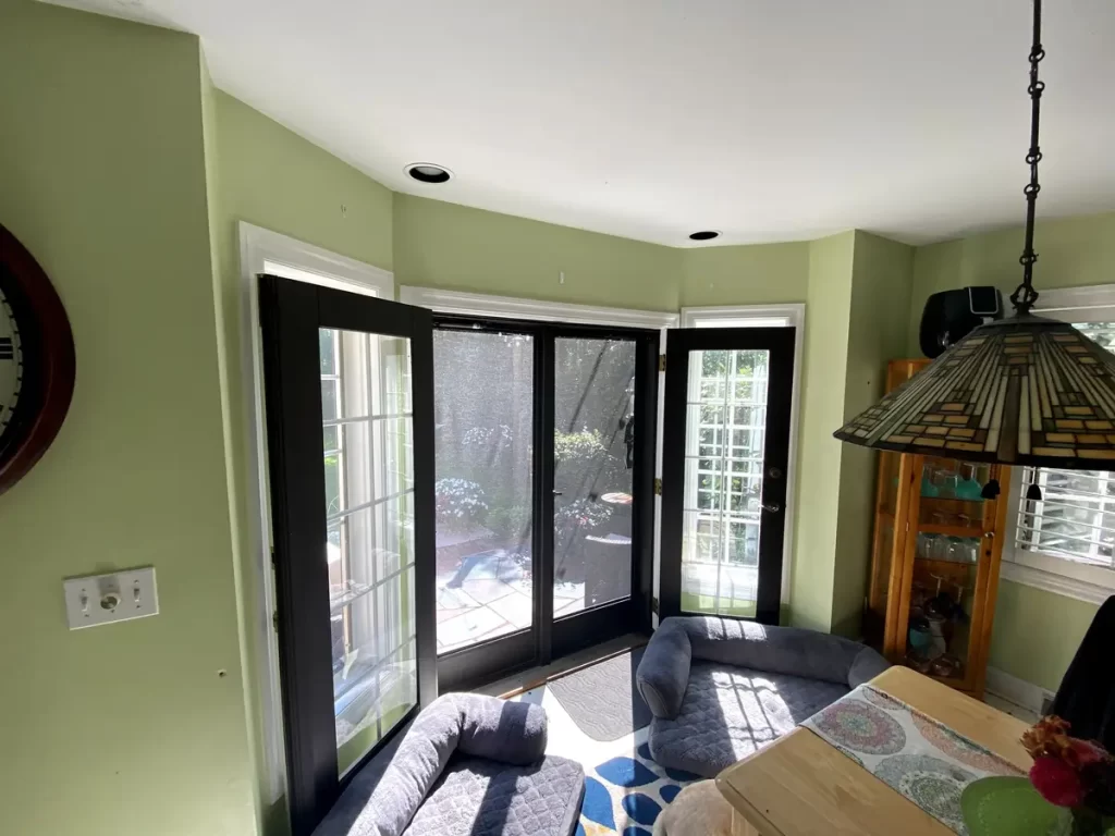 Kitchen dining area with large windows and patio doors in Buffalo, NY before renovation.