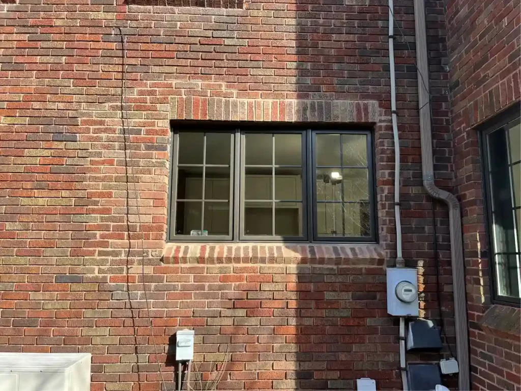 Updated kitchen window exterior with black trim in a brick wall in Amherst, NY as part of a renovation by Stately Kitchen and Bath.