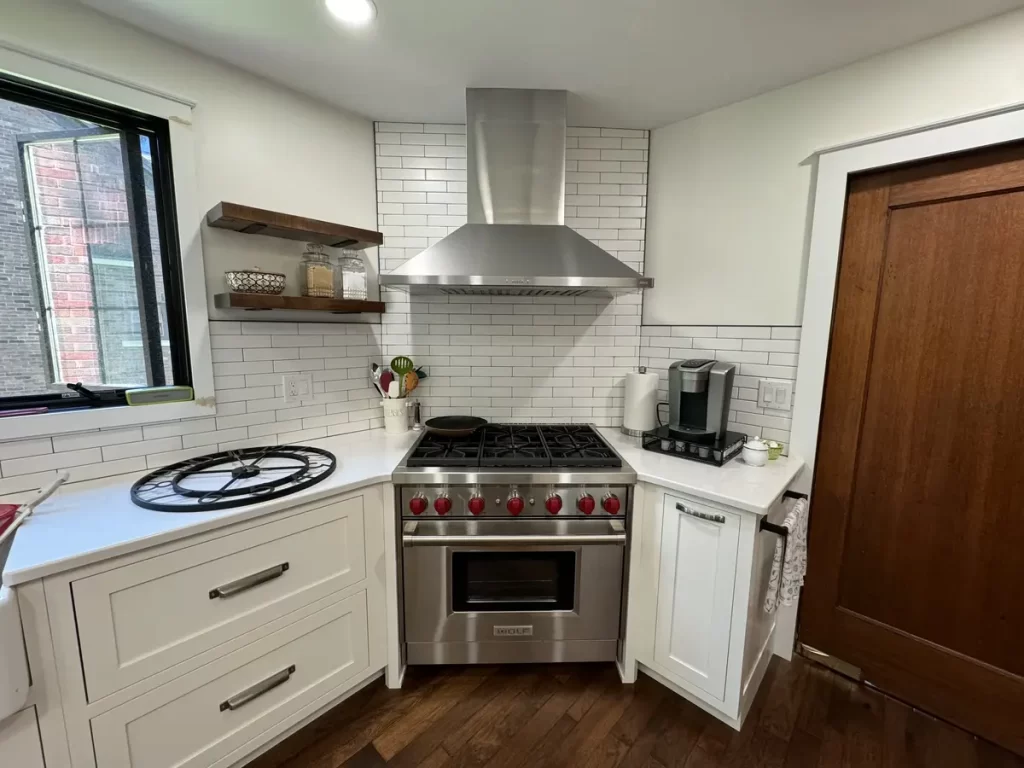 Modern kitchen corner with stainless steel range, white subway tile backsplash, and floating shelves in Amherst, NY after remodel by Stately Kitchen and Bath.