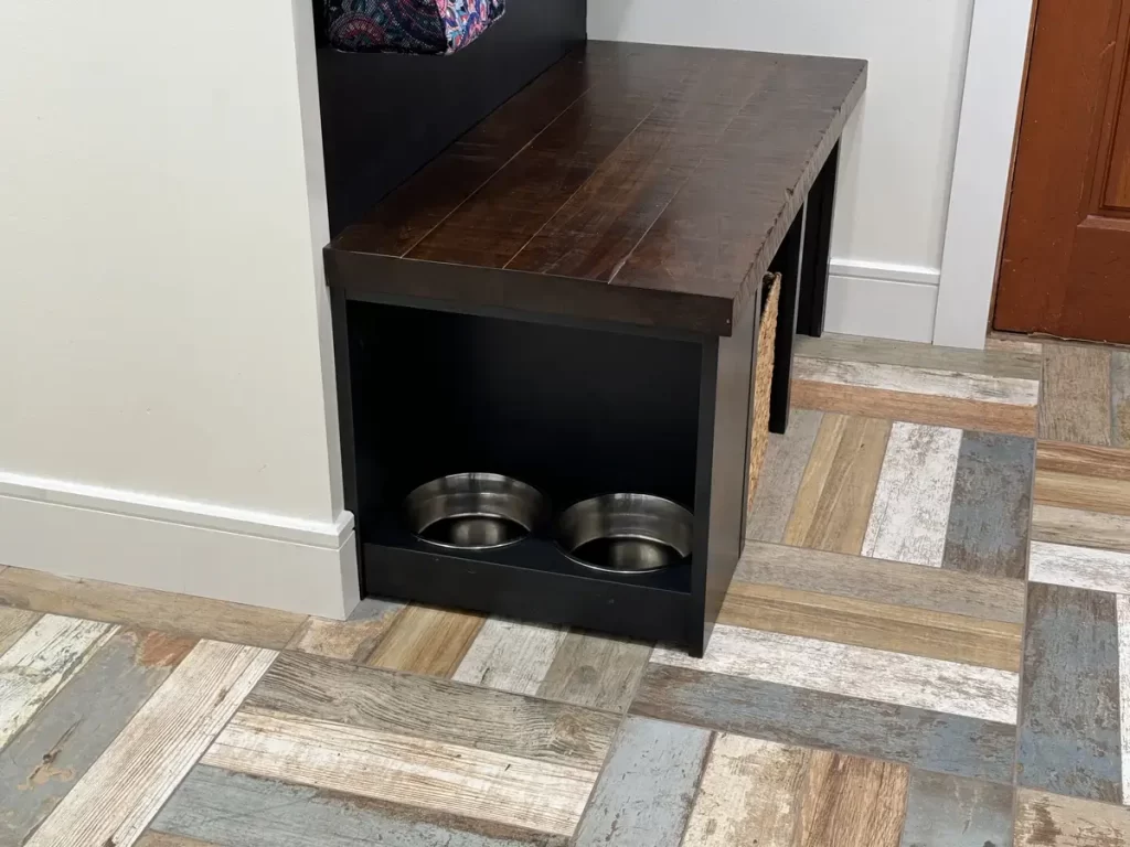 Built-in dog feeding station with wooden bench and storage in a remodeled mudroom in Amherst, NY by Stately Kitchen and Bath.