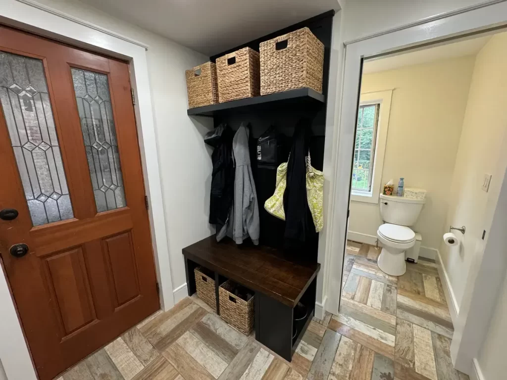 Renovated mudroom with wooden bench, coat hooks, and storage baskets in Amherst, NY by Stately Kitchen and Bath.