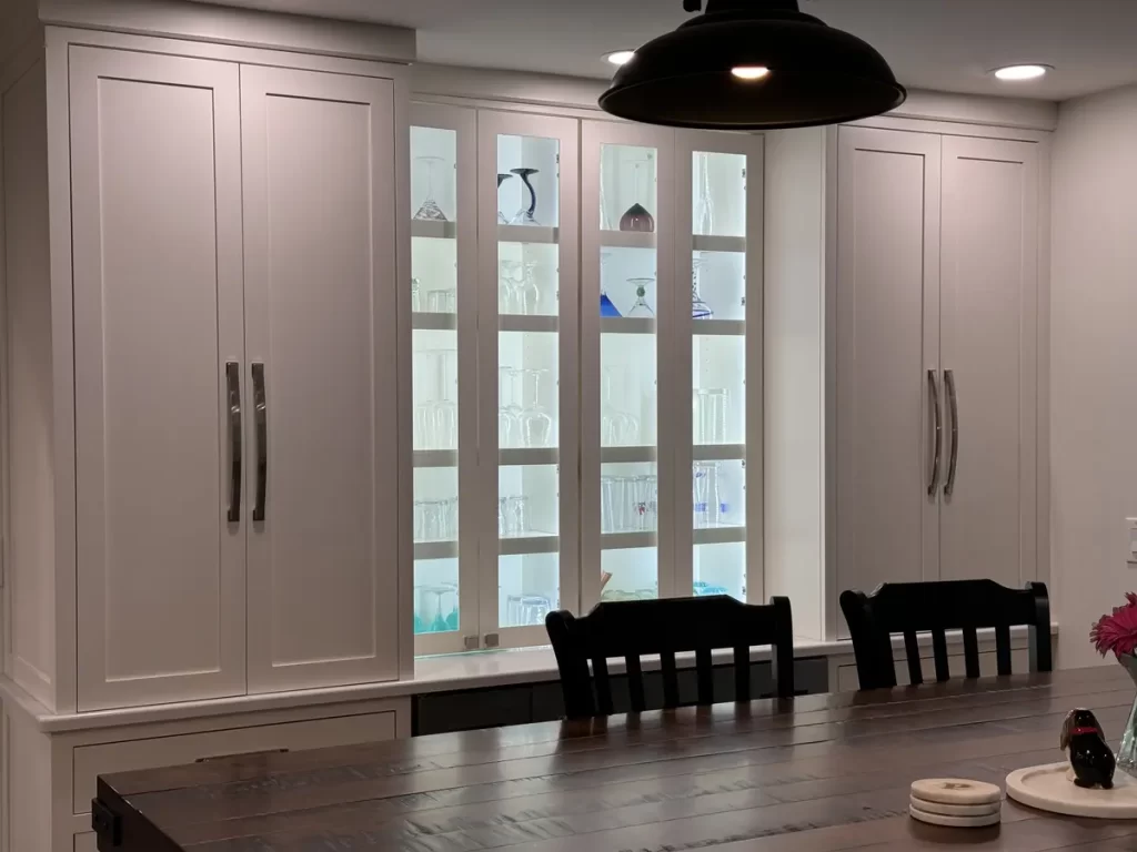 Elegant built-in glass-paneled cabinet in dining area showcasing glassware in Amherst, NY after renovation by Stately Kitchen and Bath.