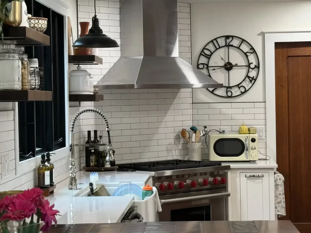 Modern kitchen with stainless steel hood, subway tile backsplash, and farmhouse sink in Amherst, NY after remodel by Stately Kitchen and Bath.