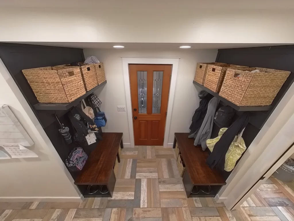 Renovated mudroom with built-in shelves, storage baskets, and wooden door in Amherst, NY by Stately Kitchen and Bath.