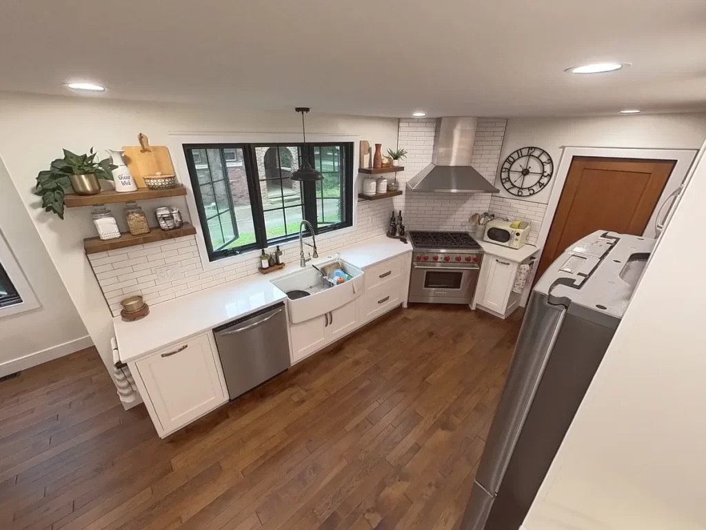 Modern kitchen with stainless steel appliances, farmhouse sink, and wooden shelves in Amherst, NY after remodel by Stately Kitchen and Bath.