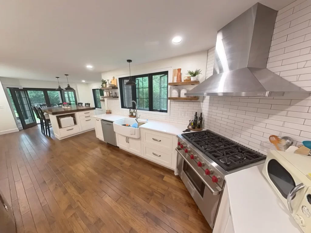 Spacious kitchen featuring a large wooden island, farmhouse sink, and stainless steel range in Amherst, NY after remodel by Stately Kitchen and Bath.