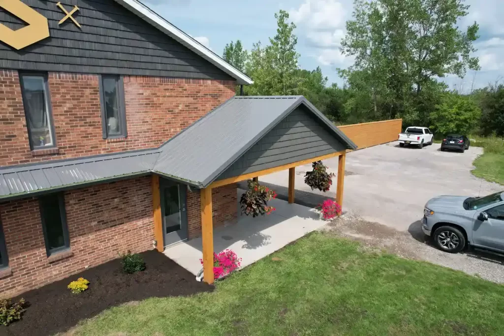 Updated entryway with a covered porch and enhanced landscaping at Stately Builders' remodeled office in Clarence Center.