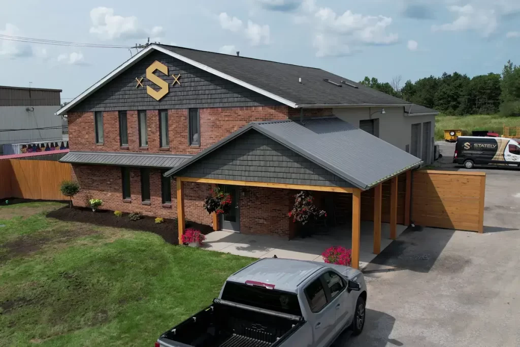 Full view of Stately Builders' Clarence Center office after exterior remodel, featuring new siding, signage, and improved landscaping.