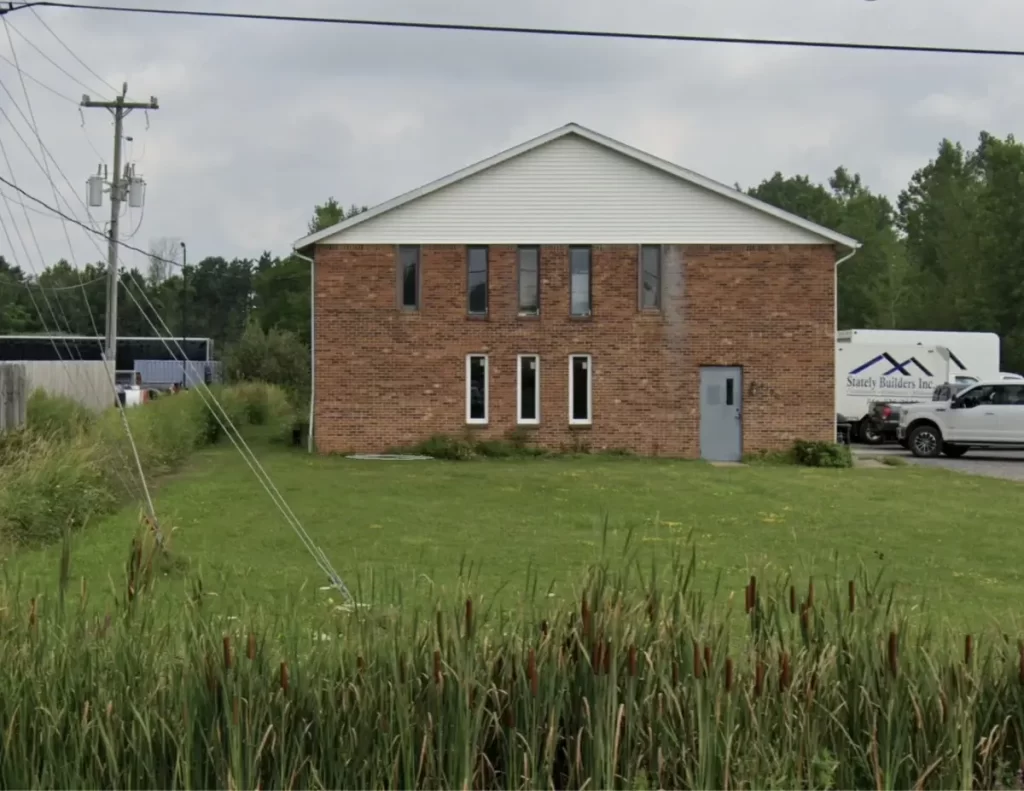 Stately Builders Clarence Center office before exterior remodel, showing the original brick facade with minimal landscaping.