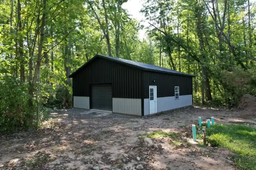 Front and side view of a modern black and gray pole barn in Clarence, NY, featuring durable metal siding and a custom garage door.