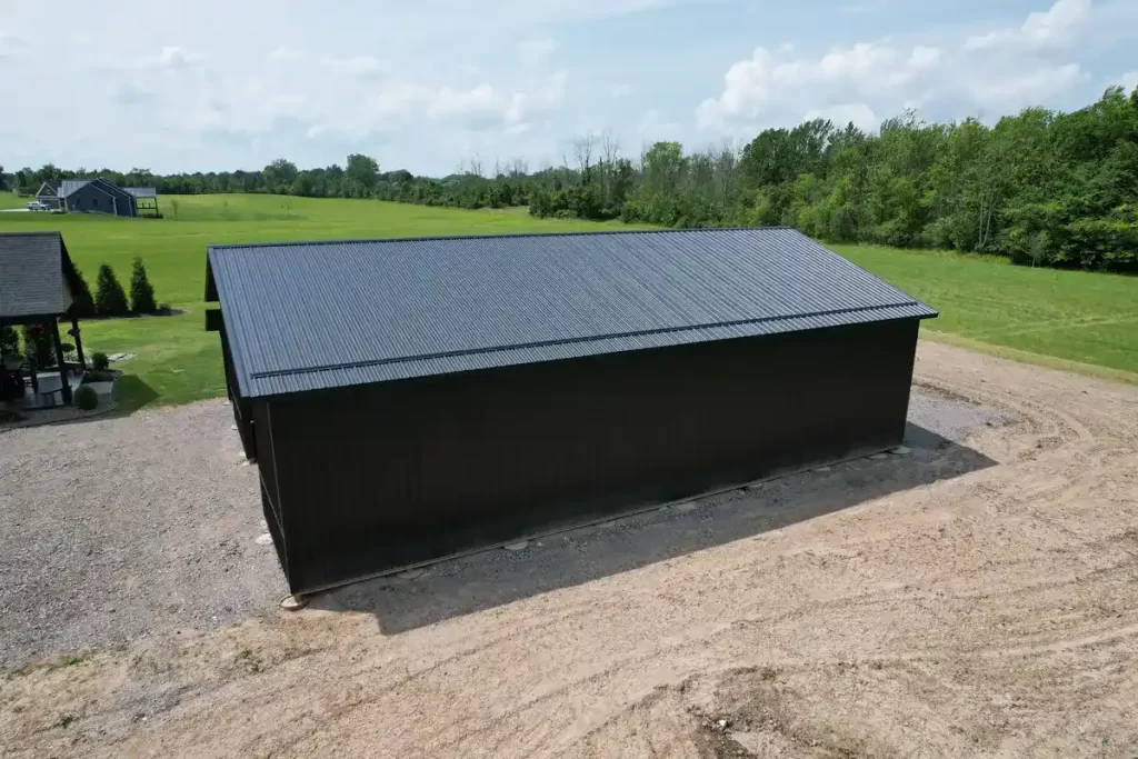 Side view of a modern matte black pole barn in Clarence, NY, highlighting the durable Everlast II Steel Panels and precision craftsmanship by Stately Pole Barns.