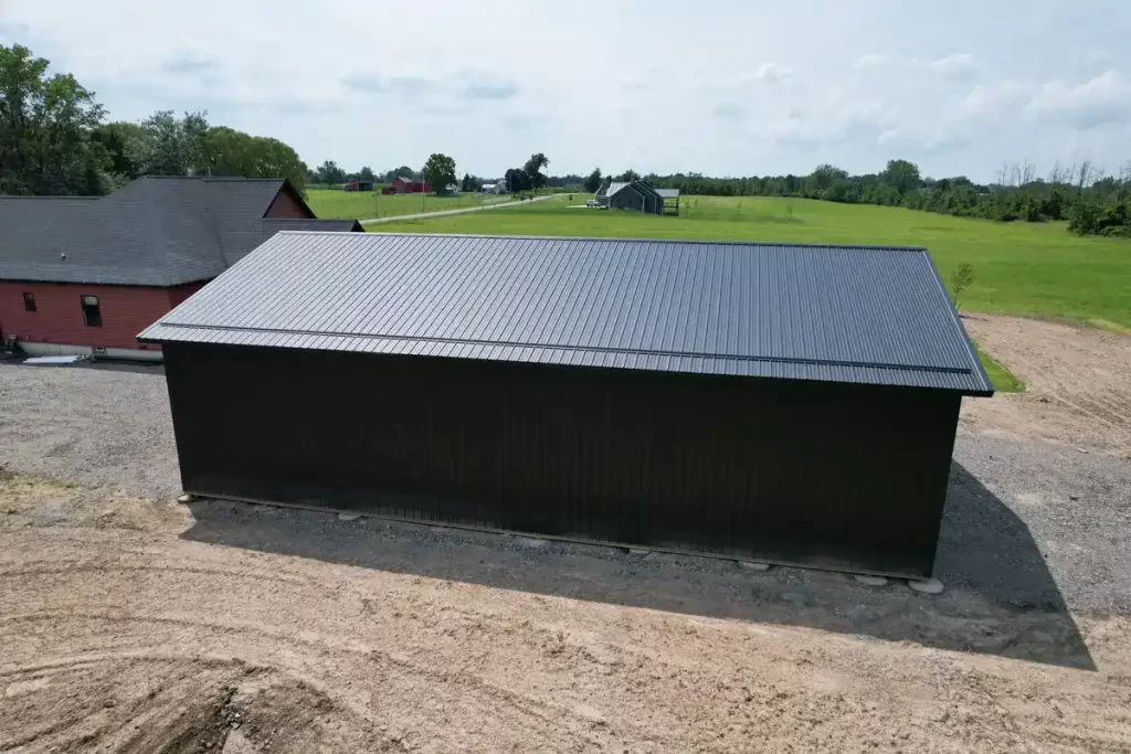 Back view of a 40x60 matte black pole barn in Clarence, NY, constructed by Stately Pole Barns with superior stability and moisture protection using Perma-Column Brackets.