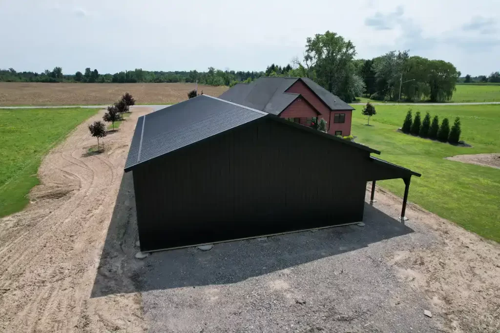 Rear view of a custom 40x60 matte black pole barn in Clarence, NY, showcasing the sturdy construction and spacious design by Stately Pole Barns.