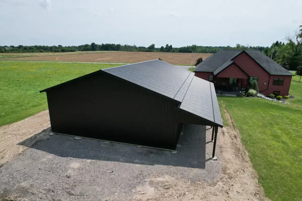 Detailed view of the back and side of a matte black pole barn in Clarence, NY, emphasizing the high-quality materials and expert craftsmanship by Stately Pole Barns.