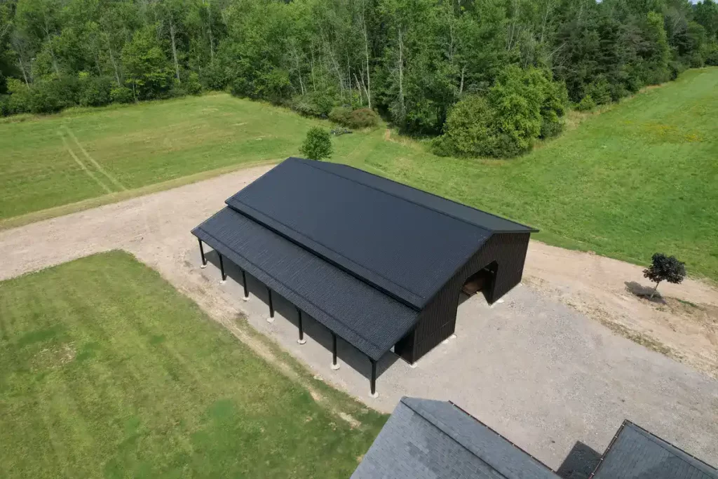 Top-down view of a durable matte black pole barn with a covered porch in Clarence, NY, emphasizing the robust construction by Stately Pole Barns.