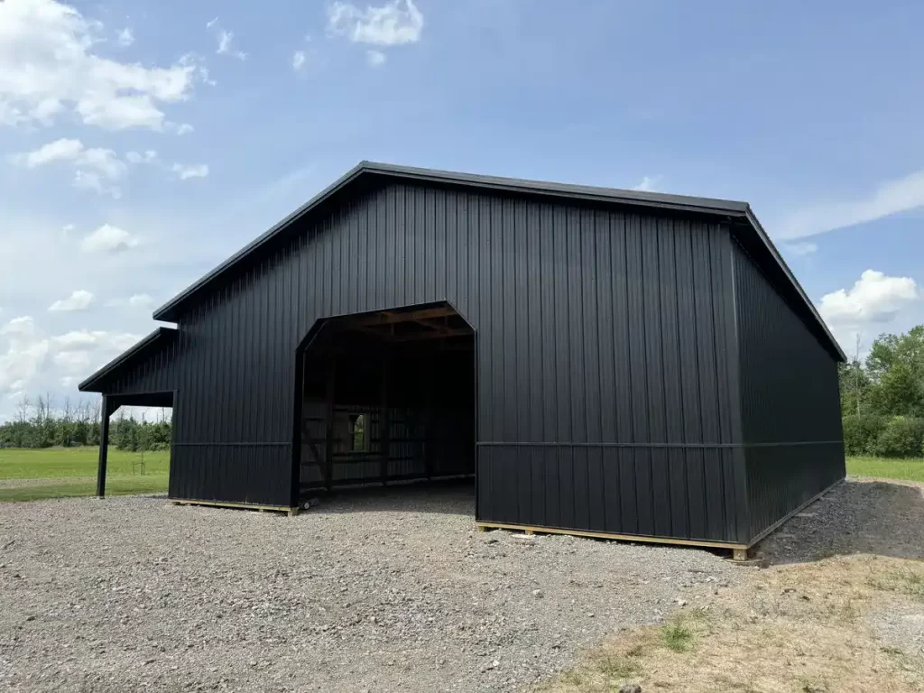 Ground-level view of the entrance to a matte black 40x60 pole barn in Clarence, NY, highlighting the spacious opening and precision-engineered structure.