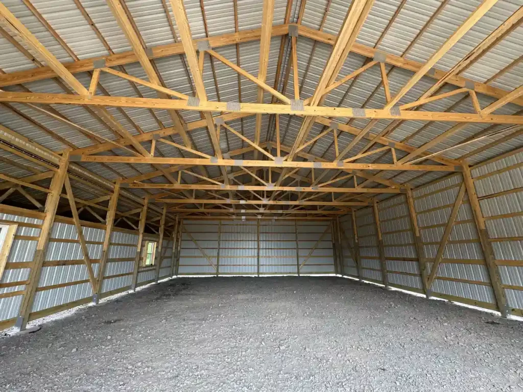 Interior view of a 40x60 pole barn in Clarence, NY, showcasing the spacious layout and high-quality wooden trusses by Stately Pole Barns.