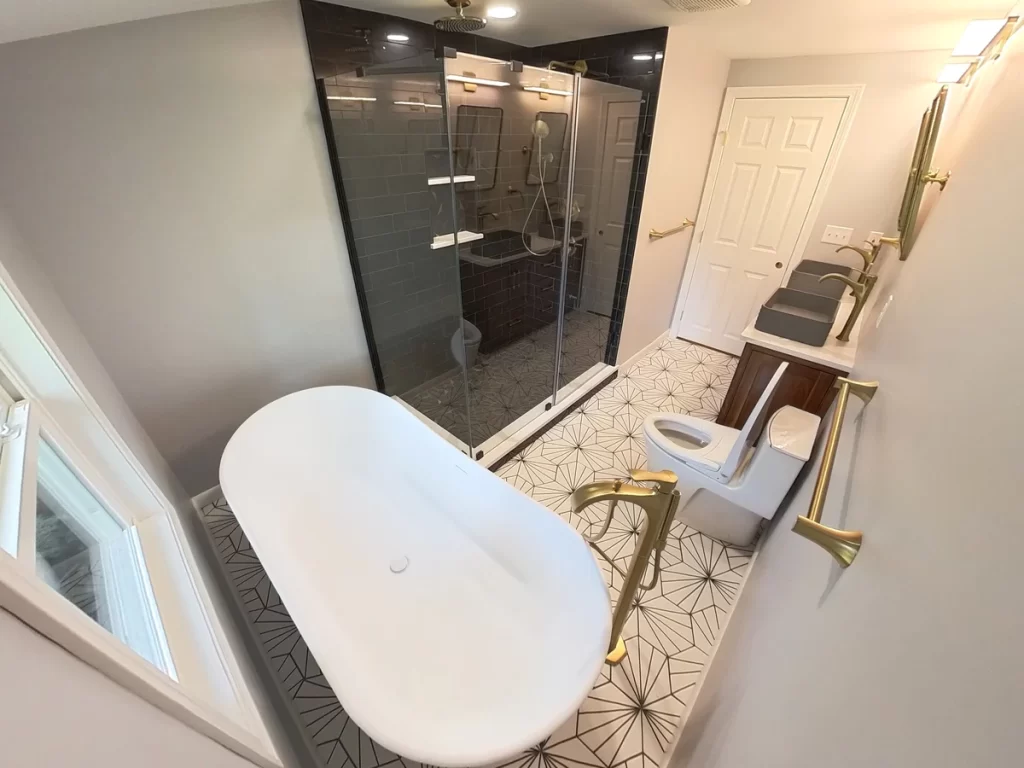 After photo of a bathroom remodel with a luxurious walk-in shower, black tile walls, and brass rain showerhead.