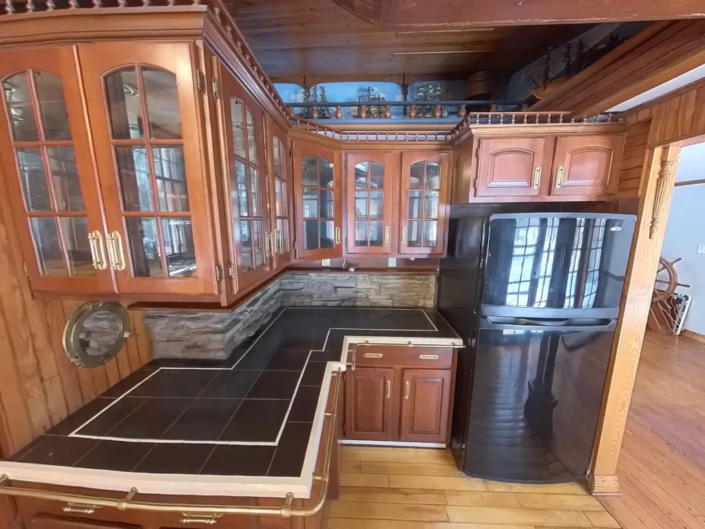 Ship-themed kitchen cabinets and countertop in the pre-remodel stage, with dark wood cabinetry and ship decor details in Elma, NY.