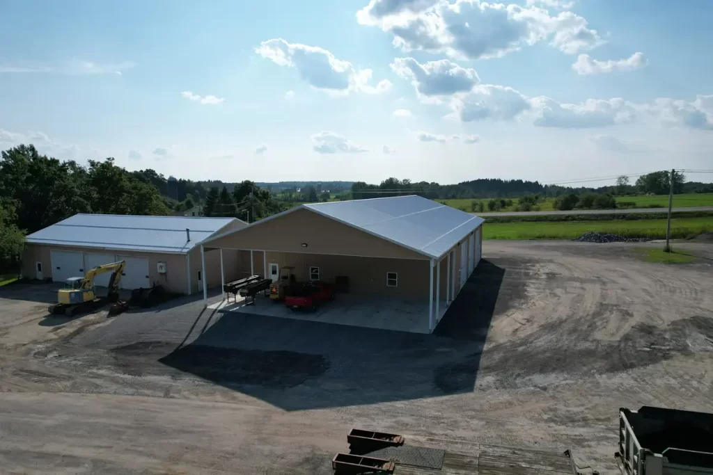 Aerial view of the completed Bennington Highway Department pole barn, highlighting the large structure, parking area, and surrounding equipment storage space, set against a scenic backdrop.