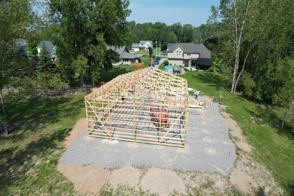 Aerial view of Stately Pole Barn framing, showing wooden structures and equipment as the post-frame barn takes shape.