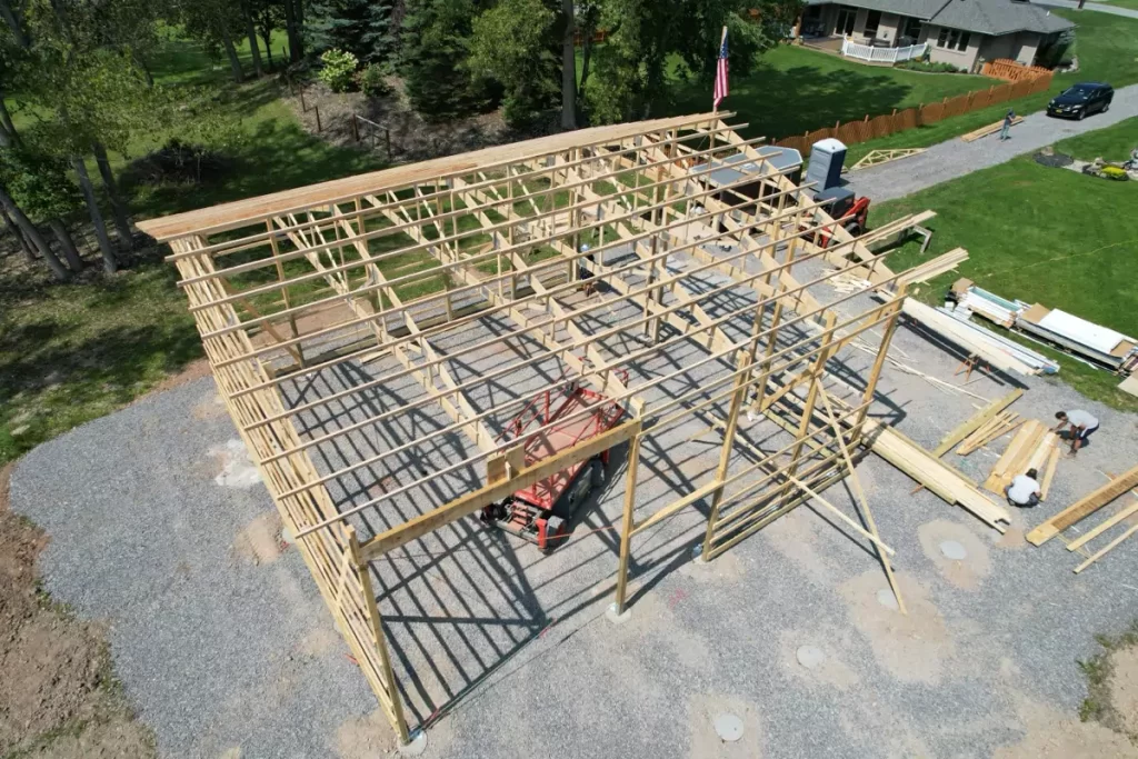 Overhead shot of Stately Pole Barn under construction, featuring wooden framing and partially installed roof trusses.