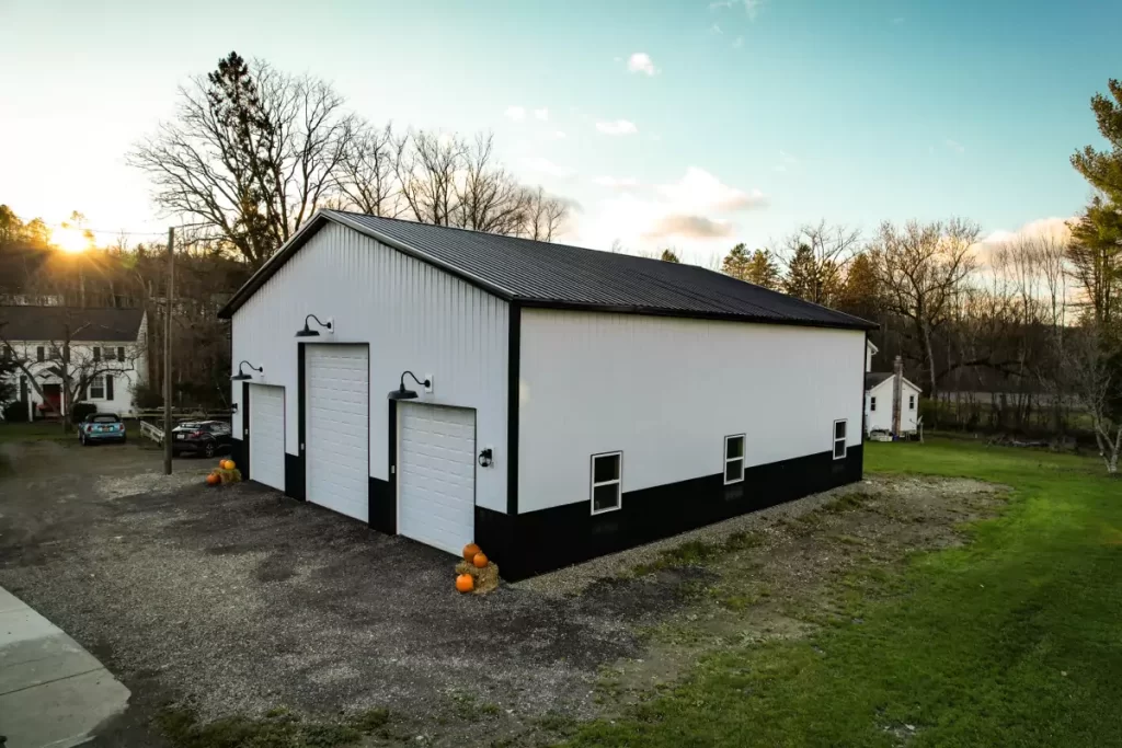 Angled view of a custom-built Stately Pole Barn in Holland, NY, featuring black wainscot and premium steel siding.