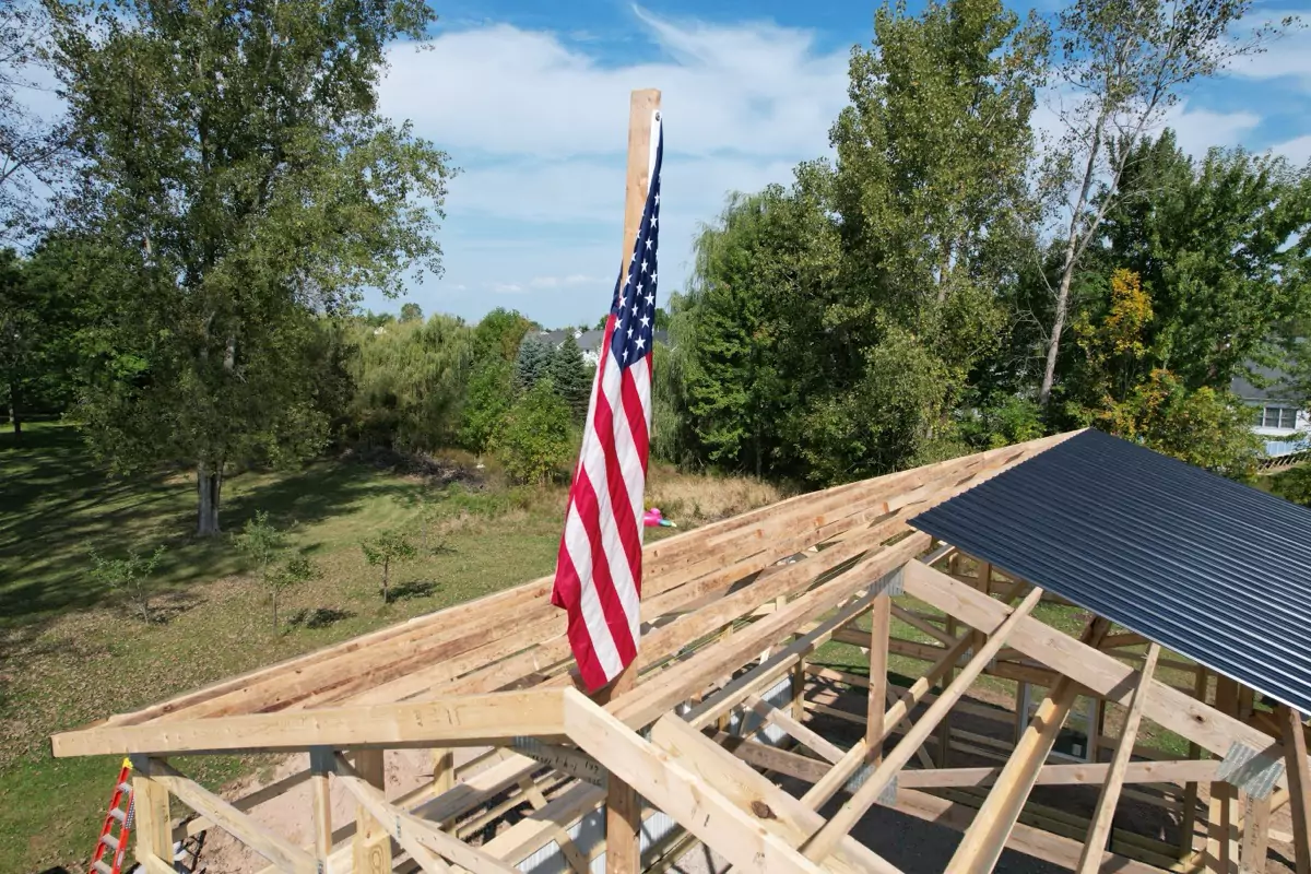 Framing of Stately Pole Barn with an American flag displayed, emphasizing craftsmanship and sturdy design.