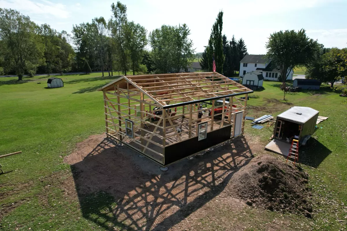 Stately Pole Barn framing progress, showing secure trusses and wood beams for strong structural support.