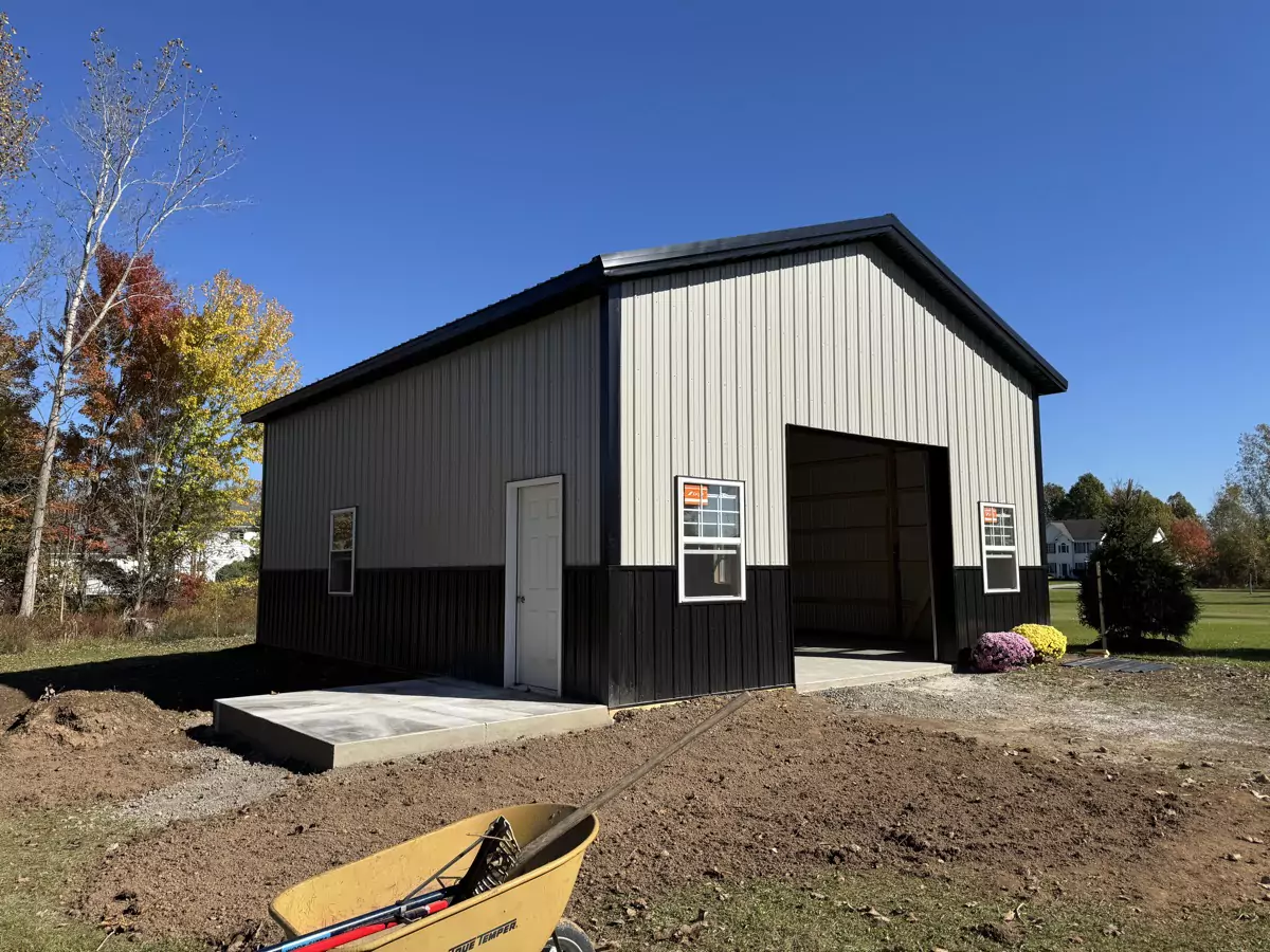 Stately Pole Barn exterior view with black and gray steel panels and large overhead door.