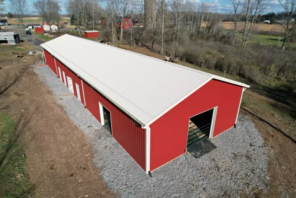 Angled aerial shot of custom red pole barn with white trim, built for durability and functionality in Gasport, NY.