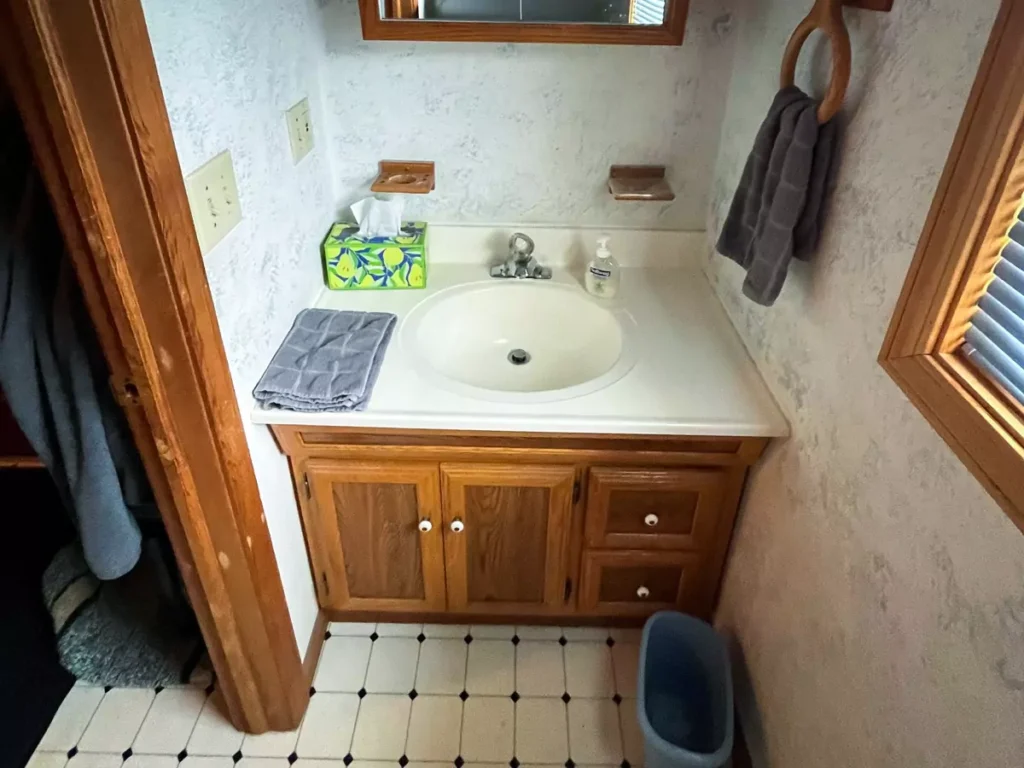 Pre-renovation bathroom with original vanity, old floor, and dated design before Stately’s modern refresh in Akron, NY.