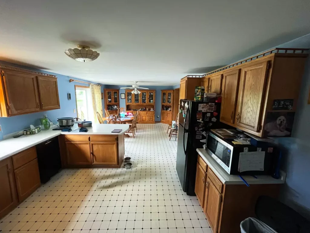 Wide view of Akron kitchen before Stately’s updates, featuring older cabinetry, old flooring, and dated fixtures.