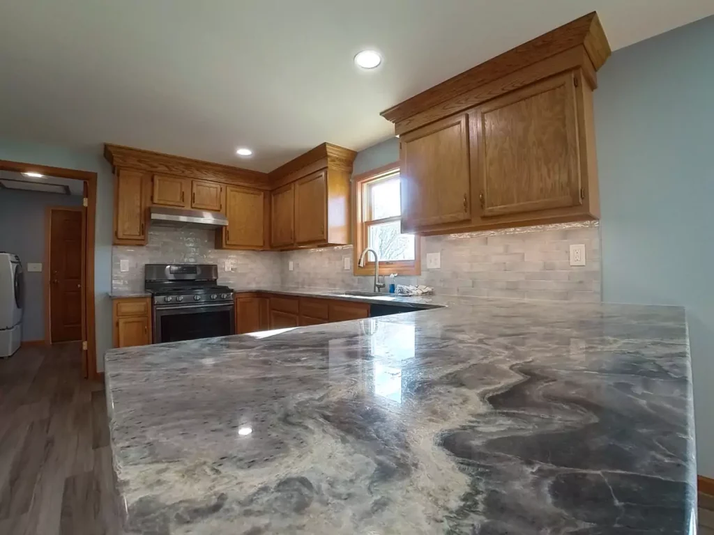 Stately-designed kitchen showcasing new stone countertops, expertly-laid backsplash, and retrofitted under-cabinet lighting.