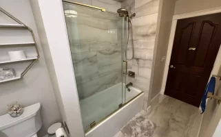 Glass-paned sliding shower door with gold accents.