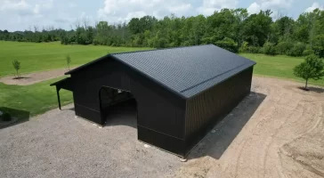 Overhead shot of a matte black pole barn built by Stately Pole Barns in Clarence, NY, featuring strong structural design with Everlast II Steel Panels and a spacious interior.